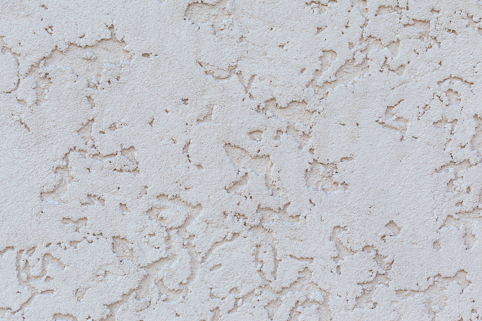 Textured background of white plaster wall with small holes on surface of building